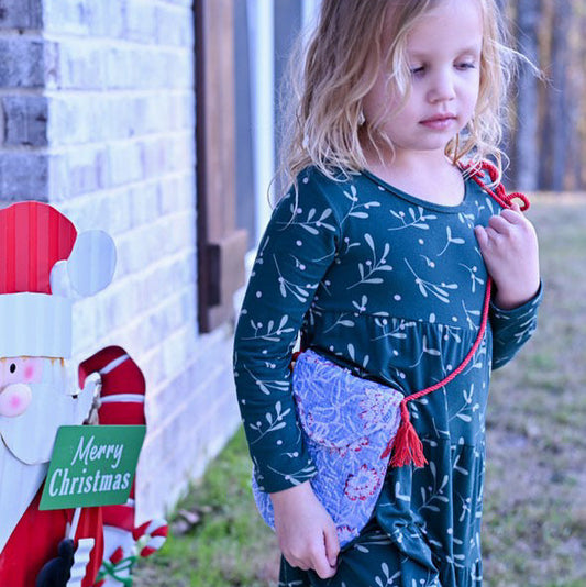 girl wearing floral cotton quilted blue purse wit red tassels