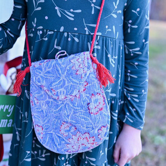 girl wearing floral cotton quilted blue purse with red tassels