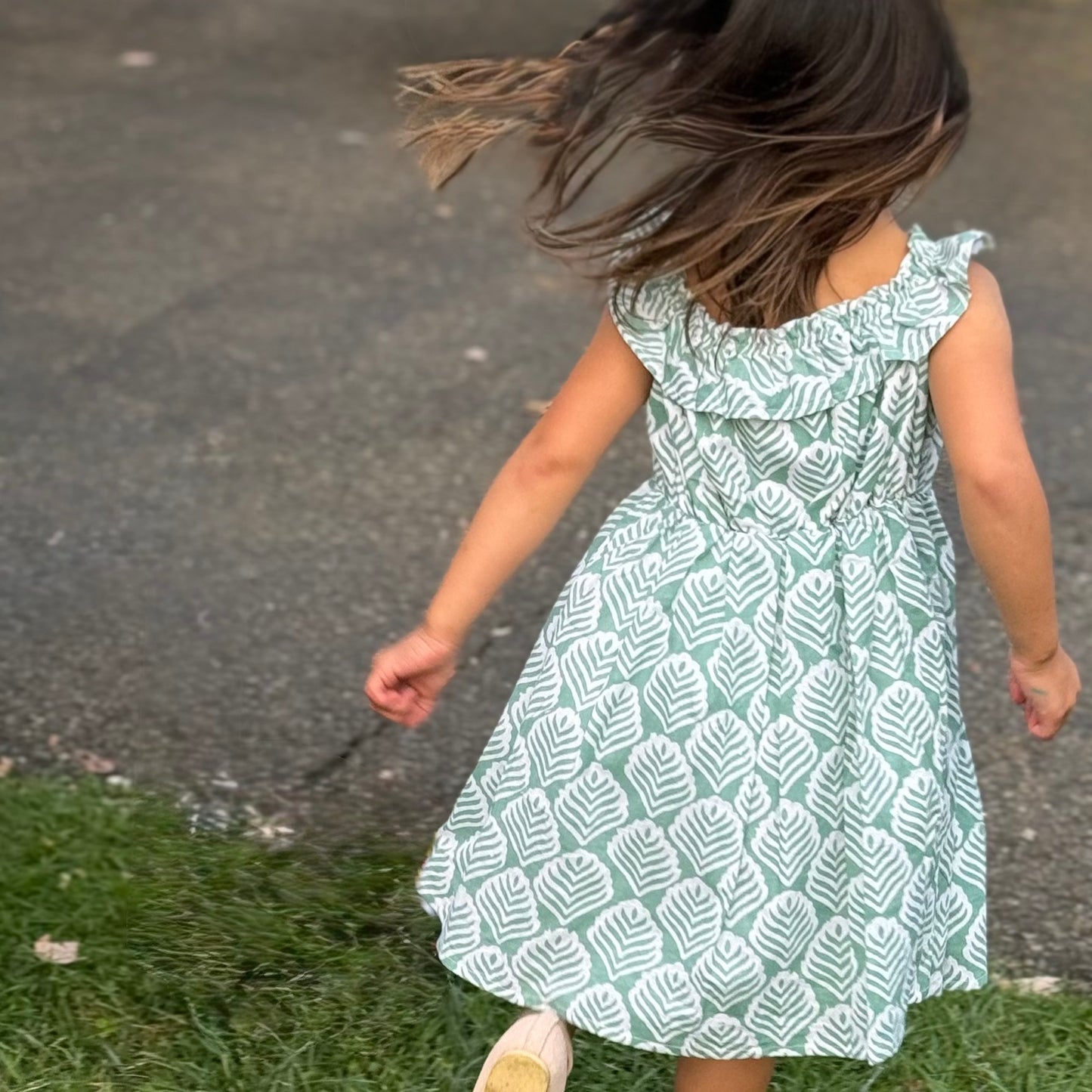 Girl happily jumping around wearing cotton summer handmade dress