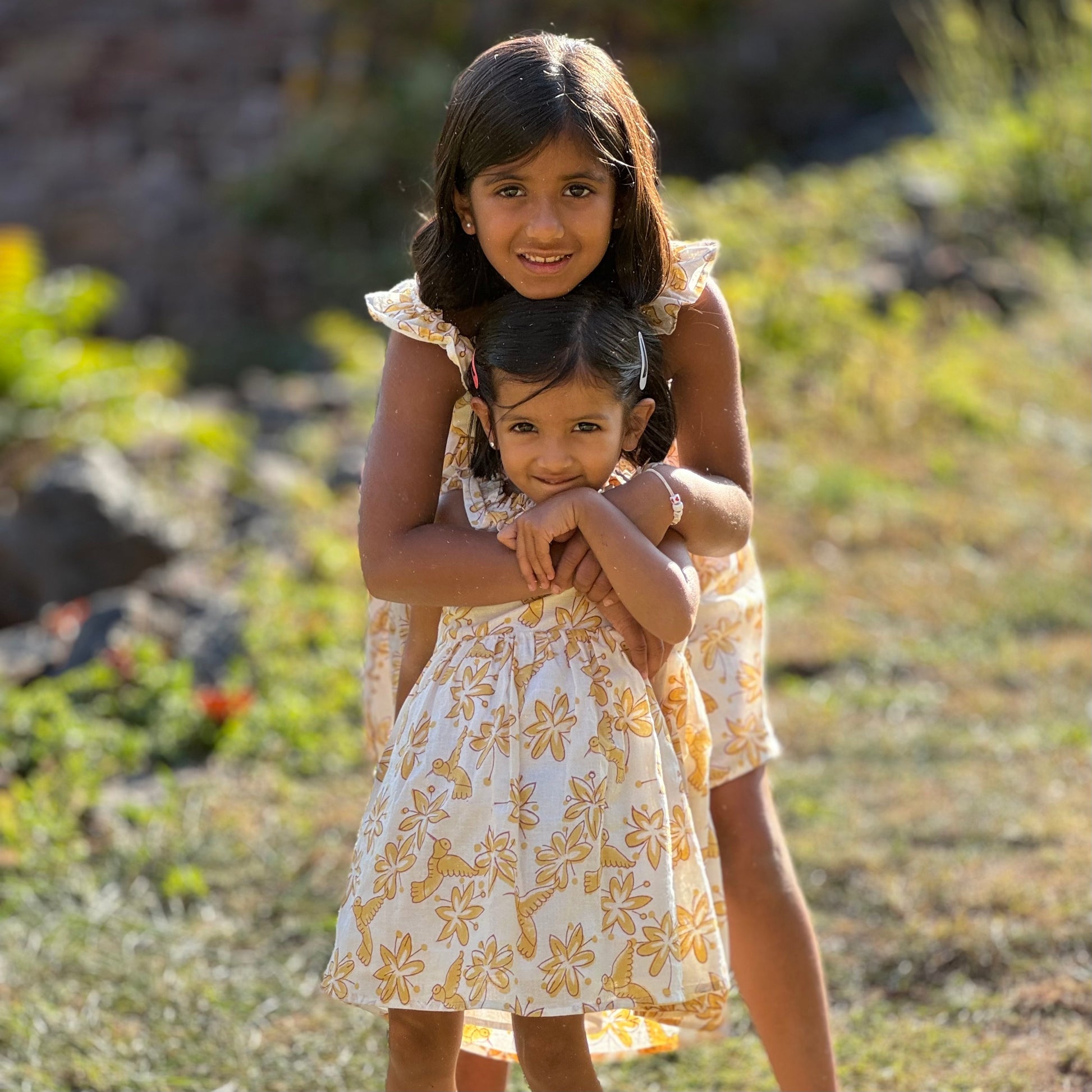 Two sisters wearing pastel floral cotton dress