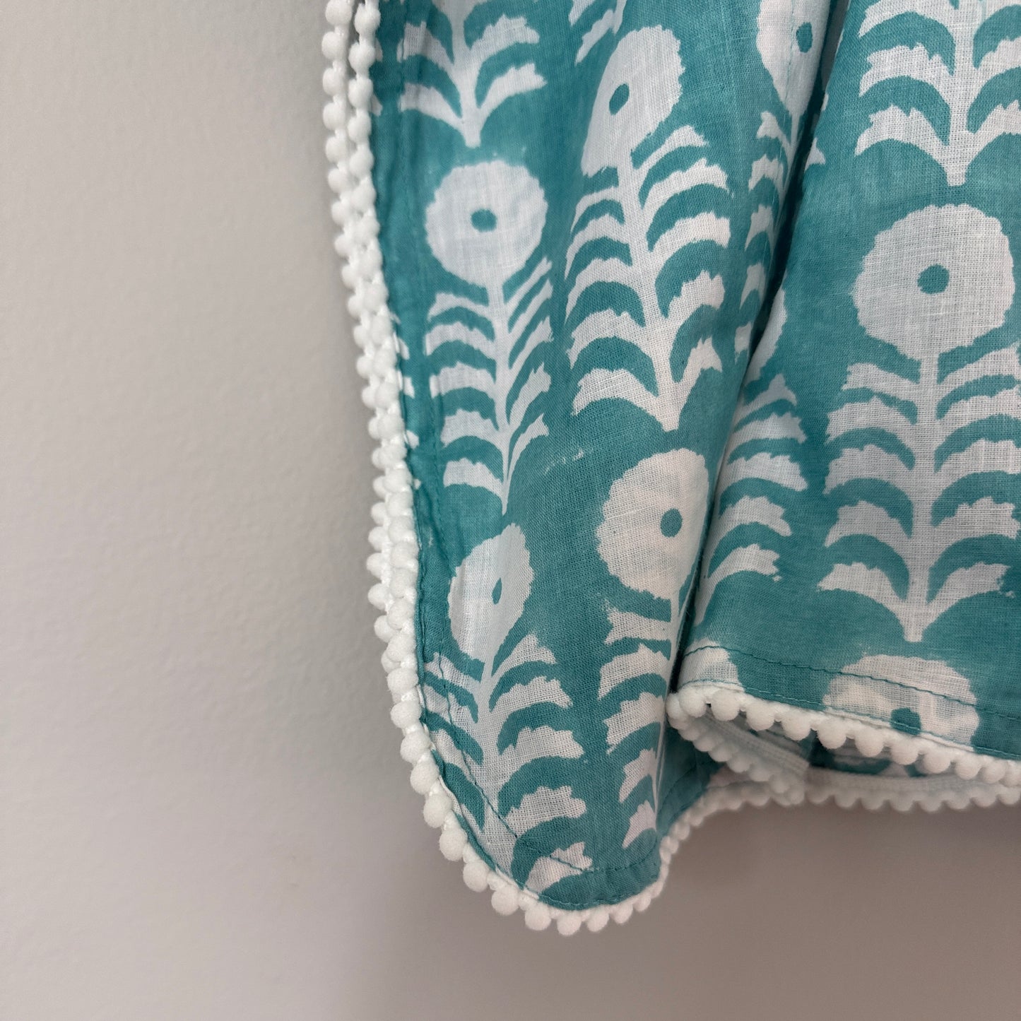 Close up of pom pom trim and adjustable tie sides on block print cotton kaftan beach cover up soft breathable fabric