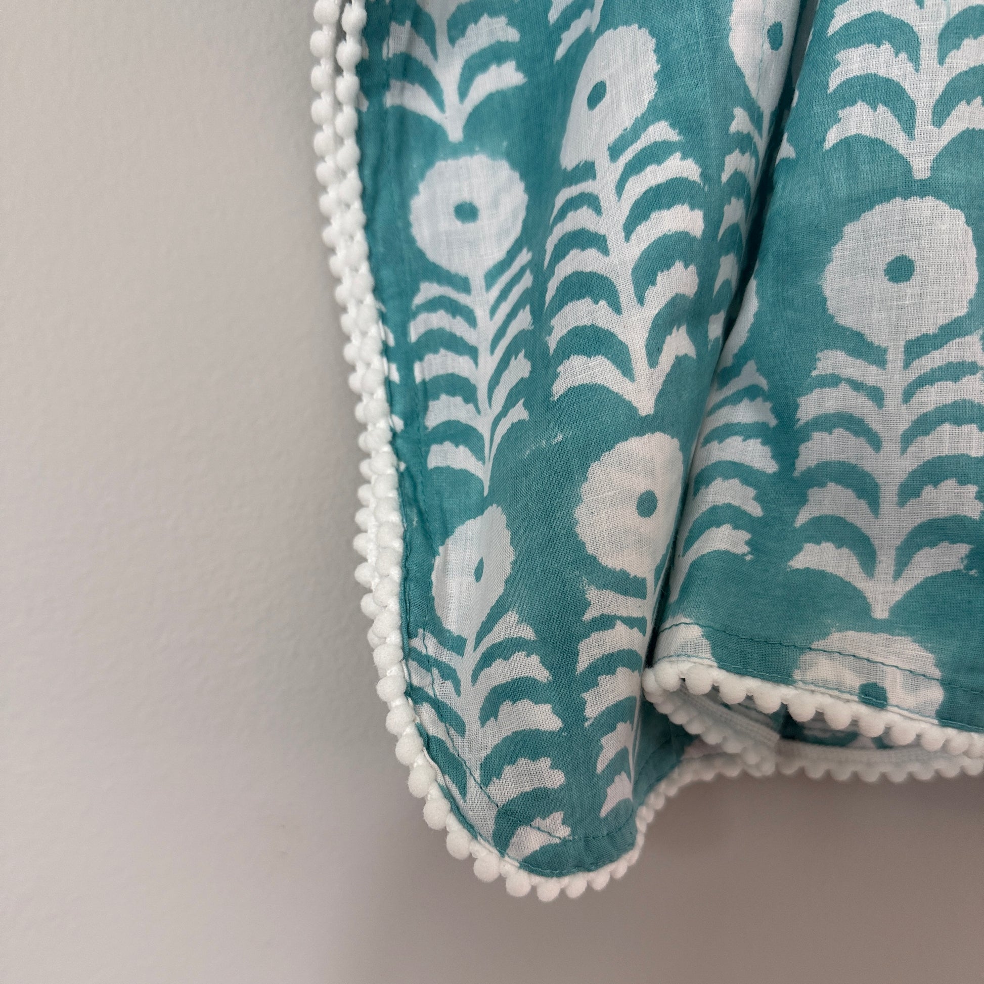 Close up of pom pom trim and adjustable tie sides on block print cotton kaftan beach cover up soft breathable fabric