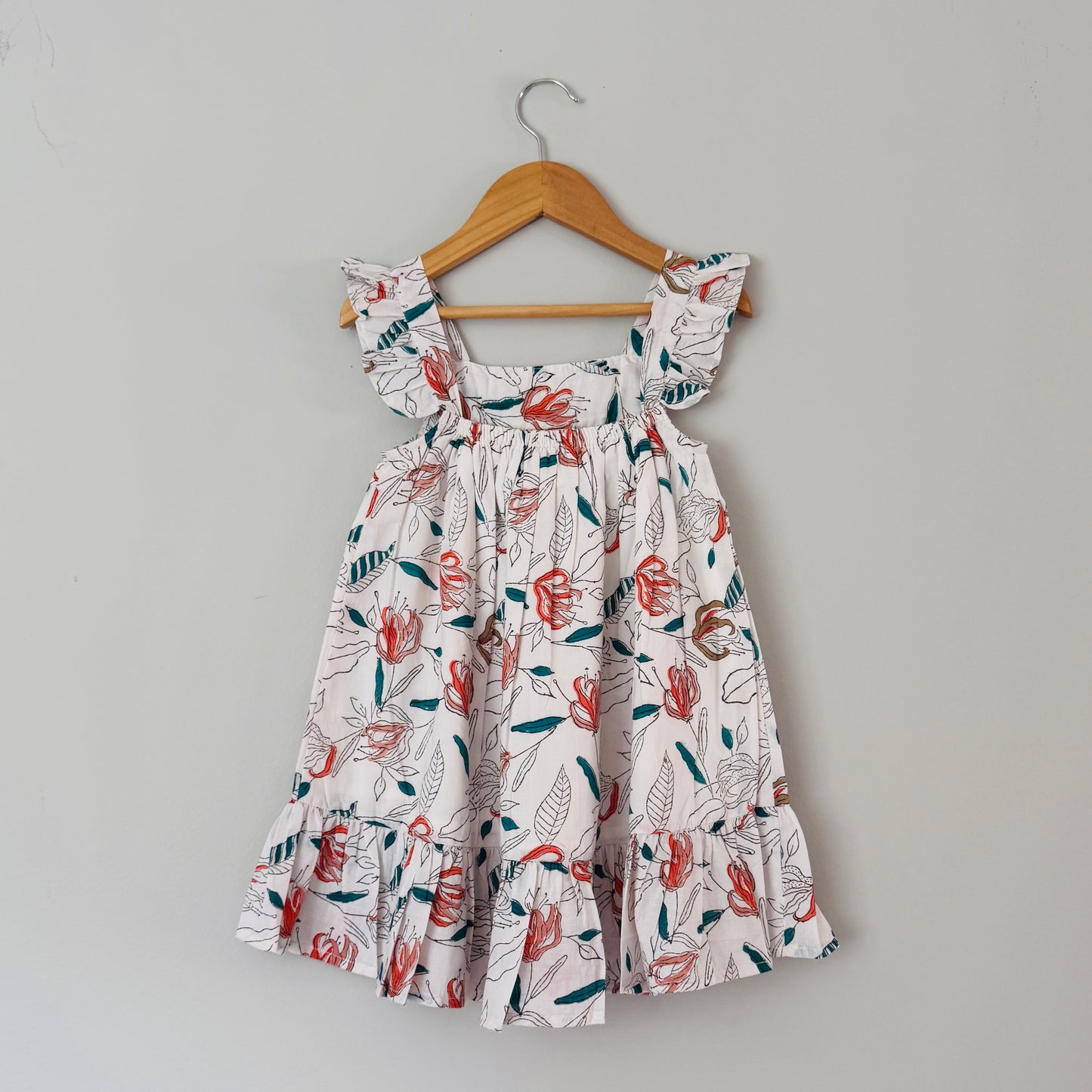 Back view of girls cotton dress with coral floral block print tiered hem lightweight summer dress for kids