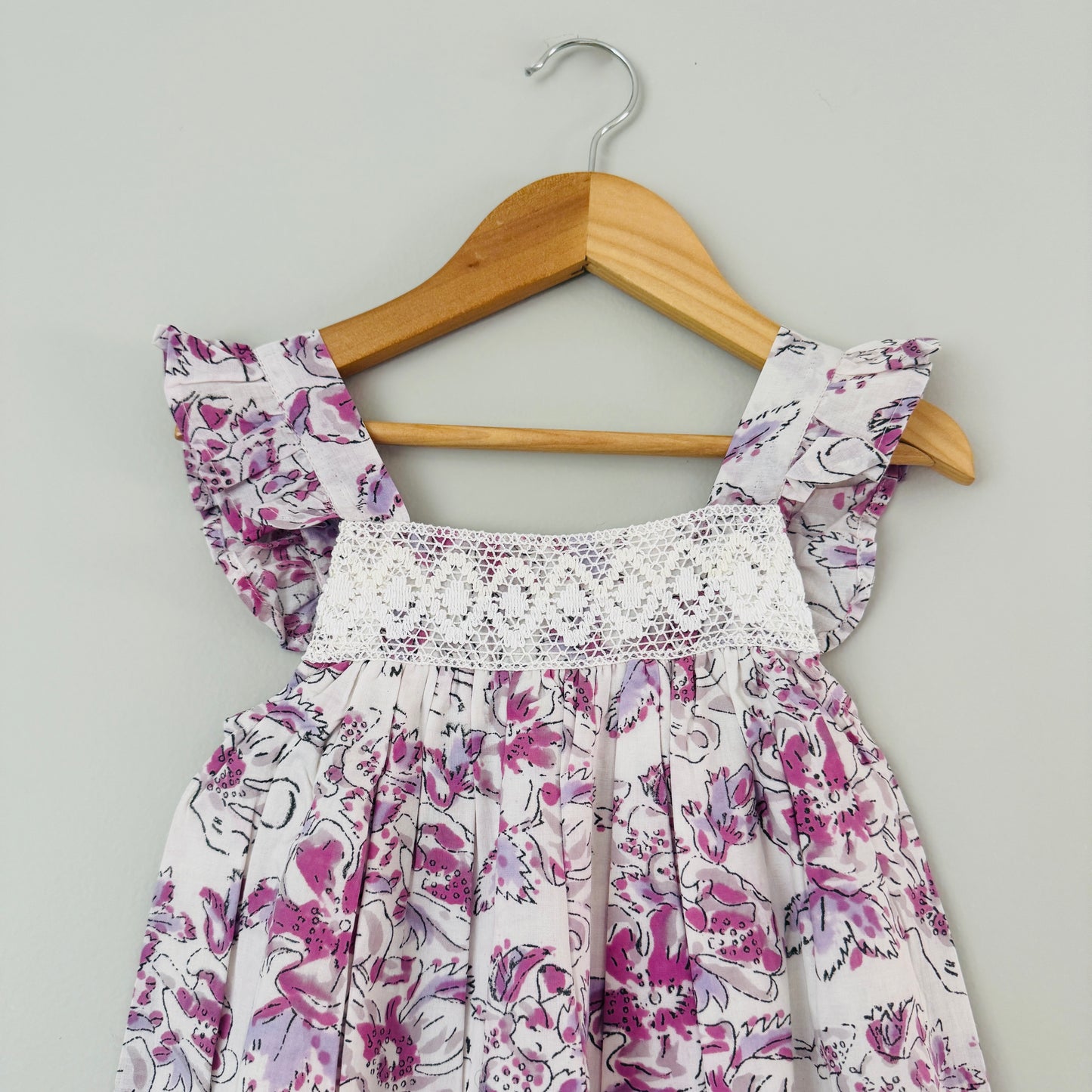 Close up of crochet detailing and lavender floral print on lightweight cotton girls summer dress soft breathable fabric