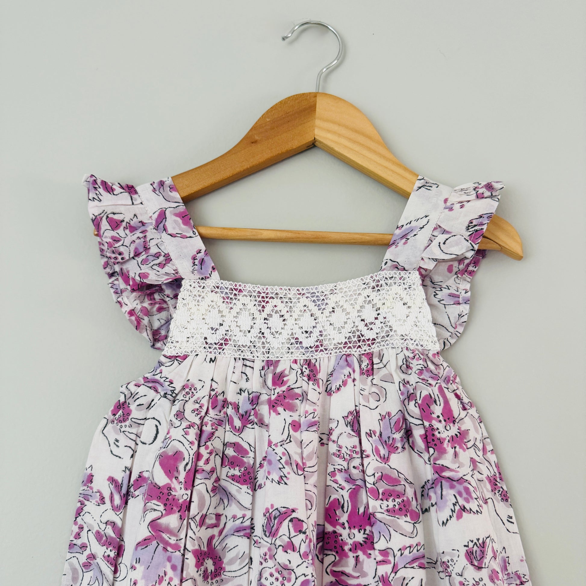 Close up of crochet detailing and lavender floral print on lightweight cotton girls summer dress soft breathable fabric
